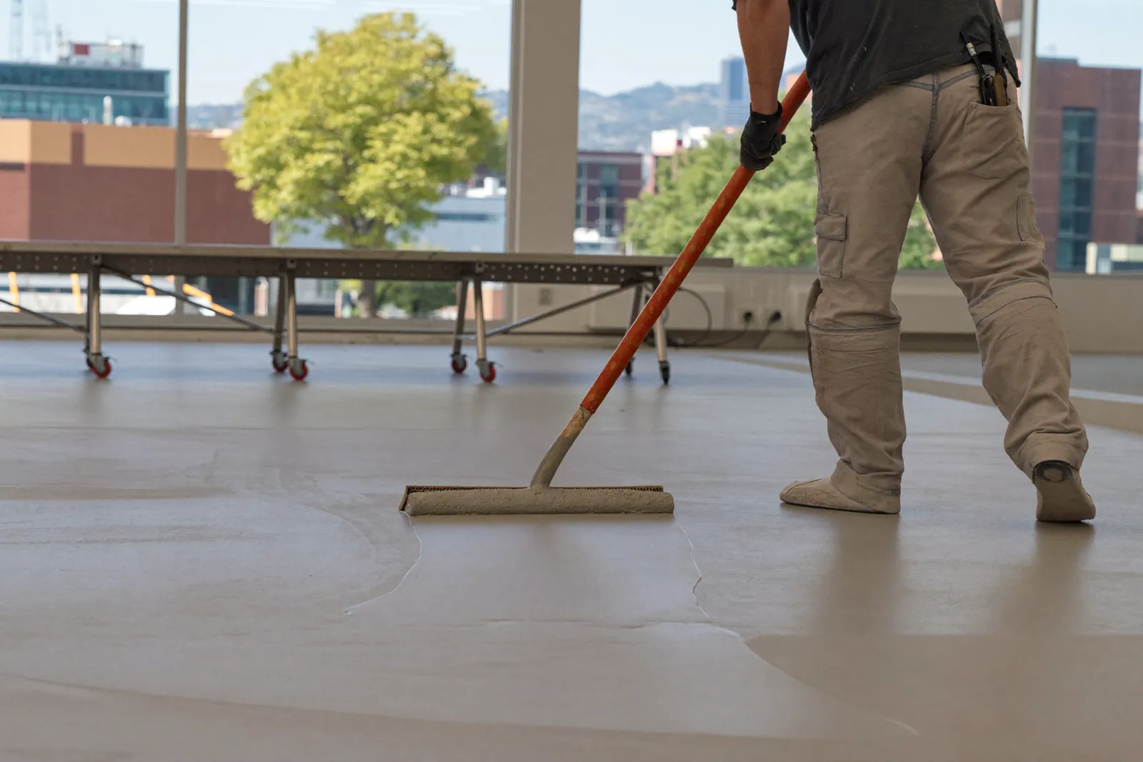 Installer spreading light gray epoxy across a lab floor with a squeegee