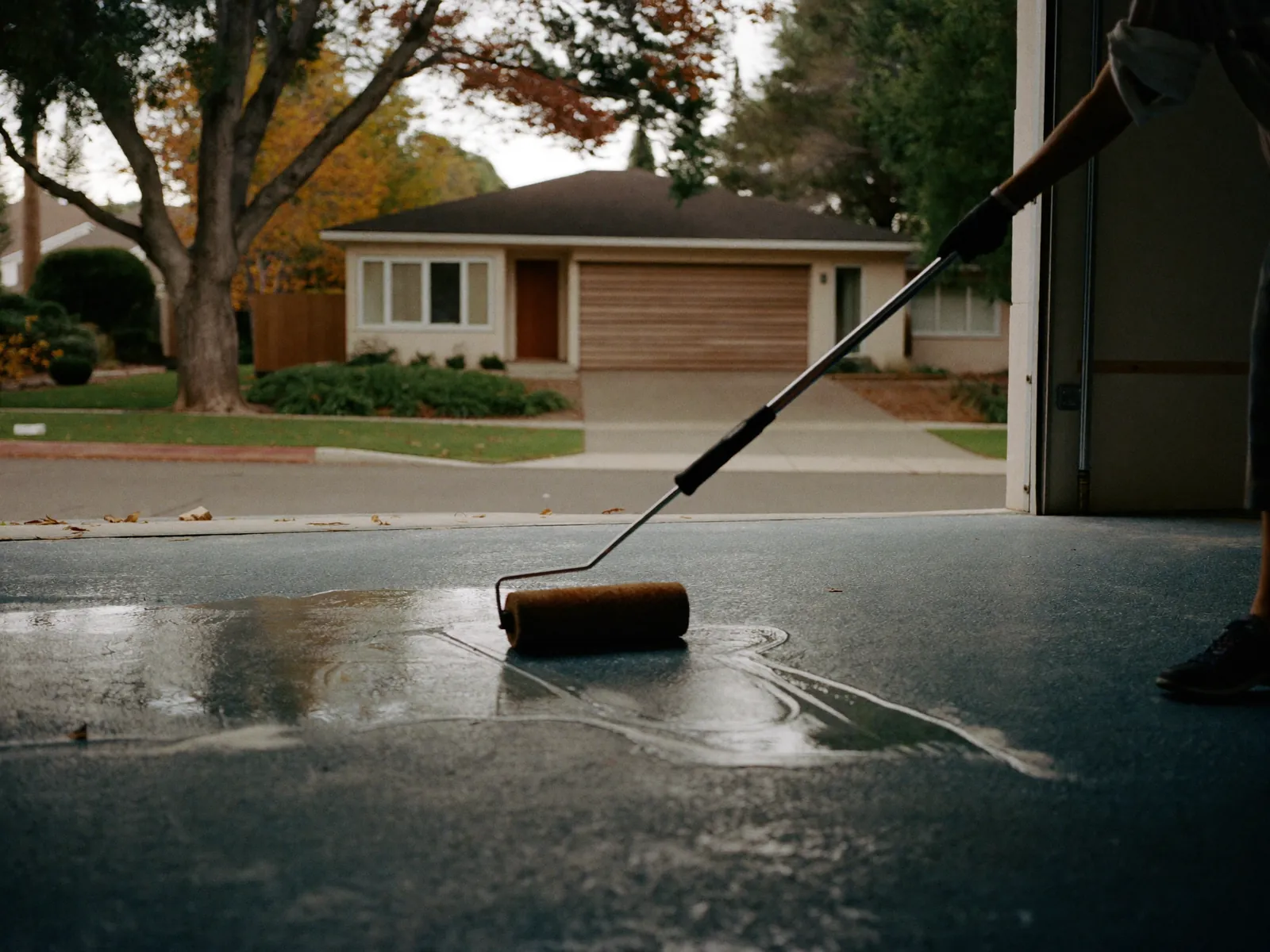 Installer rolling a clear polyaspartic topcoat over a blue-gray flake garage floor